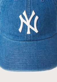 Modrá denimová baseballová čiapka s bielou vyšitou logom "NY". Textília má textúrovaný vzhľad s tvarovaným šiltom a detailmi prešívania.
