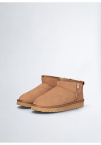 Stivaletti in suede marrone con fodera in shearling, suole in gomma piatte, collo dritto e piccolo logo accento sul lato.