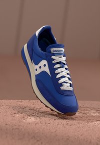 Mėlynos suknelės ir tinklelio kedai su baltais akcentais, apvaliu pirštu ir baltais raišteliais. Ant liežuvio ir šono yra Saucony logotipas. Guminis padas.