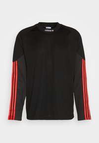Fekete, hosszú ujjú sportpóló, piros három csíkkal a hüvelyeken. Kerek nyakkivágású, és könnyű anyagból készült.