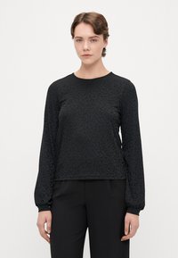 Camisola preta de mangas longas com um padrão de leopardo subtil, decote redondo e punhos ajustados. O tecido tem um acabamento liso, ligeiramente texturizado.