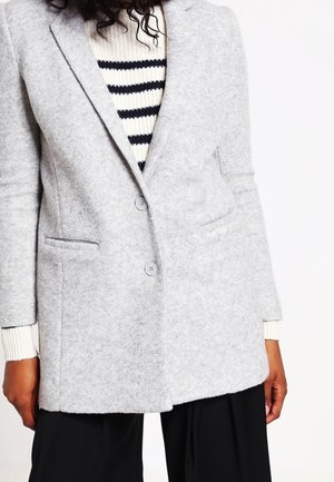 Lys grå, uldblandet blazer med en struktureret design, reverskrave, to knapper og forlommer, parret med en stribet sweater underneath.