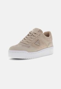Baskets en cuir beige avec un design texturé, bout rond et semelle plateforme blanche. Comprend un logo bien visible sur le côté et des lacets plats.