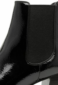 Stivale alla caviglia in pelle verniciata nera con un pannello elastico texturizzato, forma elegante e un tacco a blocco a contrasto per maggiore stabilità.