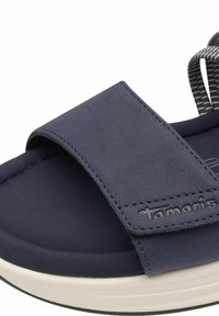 Námořnické modré sandály s širokým textilním páskem a polstrovanou podrážkou. Obsahují zdobený akcentový pásek a vyražené logo značky blízko spodní části.