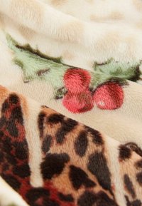 Fleece-tæppe med blød tekstur, festligt print af kristtorn og bær samt et leopardmønster i jordfarver.