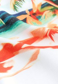 Mönstrat tyg med livfulla tropiska motiv i orange, grönt och blått på en vit botten. Texturen verkar slät och lätt.