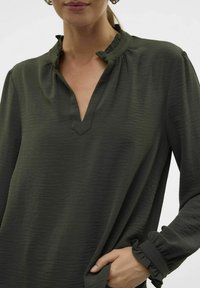 Donkergroene blouse met een gerimpelde kraag, V-hals en gathered manchetten. Glad textuur met een subtiel patroon, ontworpen voor een comfortabele pasvorm.
