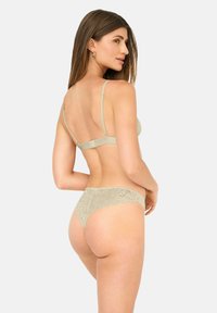 Hellbeige Spitze Lingerie-Set bestehend aus einem Bralette mit verstellbaren Trägern und einem passenden Bikinislip mit gewellten Spitzenkanten.