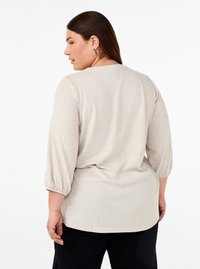 Pullover top beige chiaro con maniche a tre quarti, vestibilità rilassata e texture morbida. Orlo arrotondato e dettagli di cucitura sottili sulle maniche.