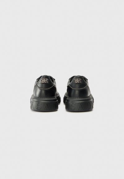 Baskets en cuir noir avec une finition texturée, dotées d'une semelle épaisse et d'un logo en relief à l'arrière. Couture décorative le long des côtés.