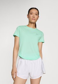 Mäta zelené športové tričko s krátkymi rukávmi, okrúhlym výstrihom a subtílnym logom Nike; v kombinácii s bielymi šortkami. Hladká, ľahká tkanina.