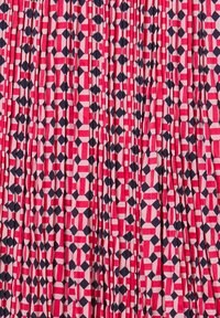 Tessuto geometrico rosso e rosa con forme a diamante nere e accenti beige chiaro, mostrato con pieghe verticali.