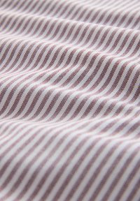 Tissu en coton présentant un motif ondulé de rayures blanches et bordeaux. La texture est lisse avec un léger éclat, mettant en valeur la profondeur du tissu.