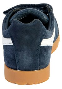 Blå mocka sneakers med en vit rand, har en rund baksida och en sula av gummigummi med ett strukturerat mönster.