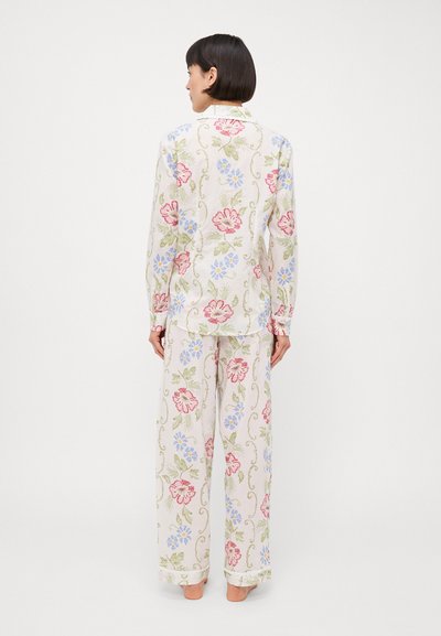 Pysjamasett med blomster mønster som inkluderer en langermet skjorte med knapper og vide bukser, laget av lett stoff i pastellfarger – rosa, blå og grønn.