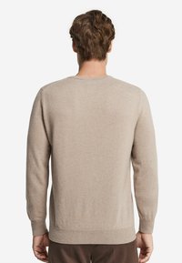 Beige tröja med långa ärmar och rund halsringning, med en mjuk textur och ribbade muddar och fåll. Inga synliga mönster eller detaljer.