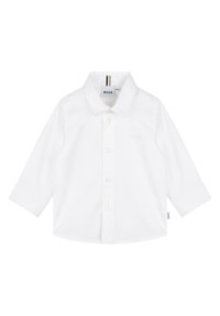 Camisa branca de manga comprida feita de algodão, com frente de botões, gola pontiaguda e uma marcação subtil no peito.