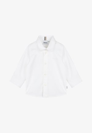 Ilgas baltas medvilninis marškinėlis su ilgomis rankovėmis, turintis sagų užsegimą priekyje, smailų apykaklę ir subtilų ženklinimą ant krūtinės.