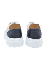 Sneakers in pelle con suole bianche, dotati di un tallone blu navy e tan e una tomaia liscia di grigio chiaro. Forma arrotondata con dettagli minimi.