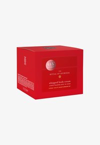 Punainen pahvilaatikko, jossa on neliömuotoilu, ja läpinäkyvä etiketti, jossa lukee "vaahdotettu vartalovoide" sekä tietoja ainesosista.