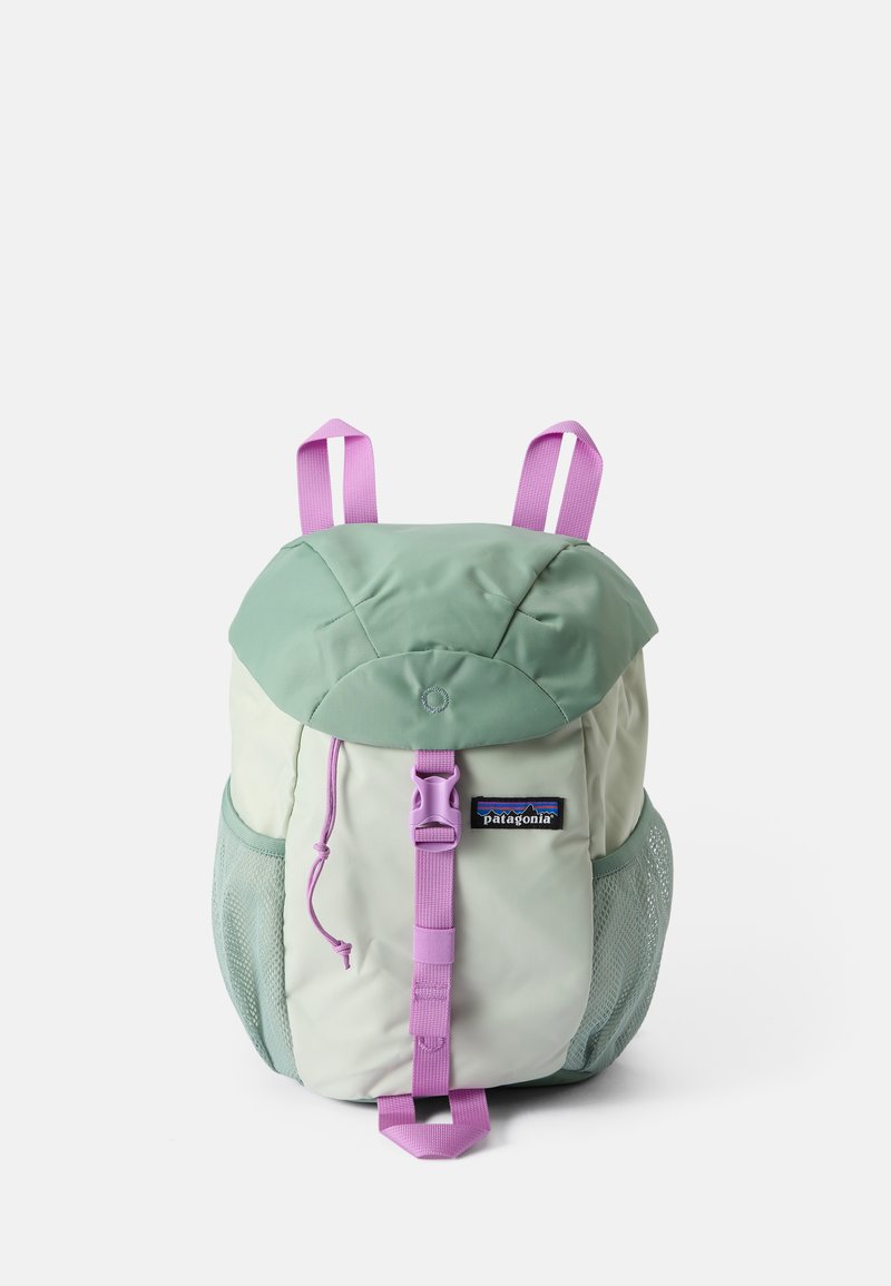 Mugursoma ar zaļu augšu un krēma apakšu, aprīkota ar purpursarkanu siksnu un sieta sānu kabatām. Iekļauj apļveida logo un zīmola uzšuvumu.