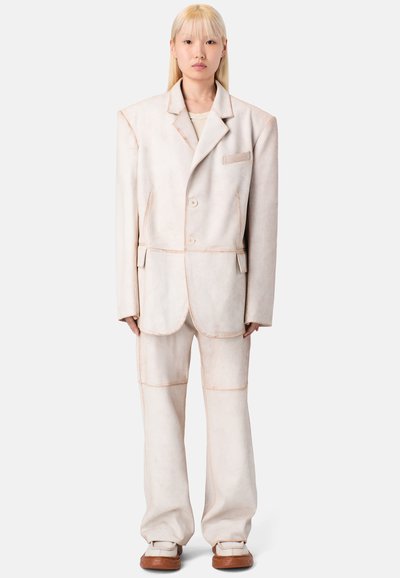 Hellbeige übergroßer Anzug aus strukturiertem Stoff mit kontrastierenden Nähten. Umfasst ein Einreiher-Jacket mit Knöpfen und passende Hose.
