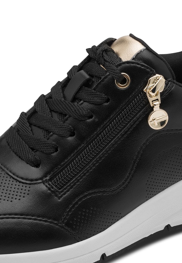 Sneaker en cuir noir avec des accents texturés, une fermeture éclair sur le côté avec des finitions dorées, et une semelle en caoutchouc blanche. Design à lacets avec des détails perforés.