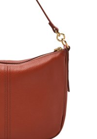 Sac en cuir marron avec une forme légèrement arrondie. Comprend une fermeture éclair sur le dessus, une fine bandoulière et des accents en matériel doré. Surface texturée.