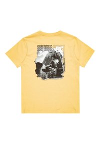 Camiseta de algodón de manga corta amarilla con un estampado gráfico en blanco y negro, que incluye texto y un detalle de foto distorsionado.