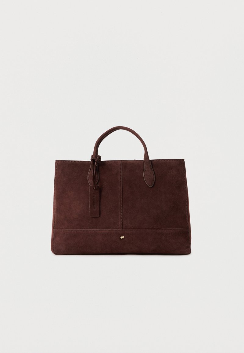 Καφέ σκούρο σουέντ ορθογώνια τσάντα χειρός με δύο λαβές και ένα μικρό χρυσό λογότυπο τοποθετημένο στο κέντρο κοντά στο κάτω μέρος σε απλό φόντο.