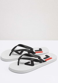 Sort flip-flops med en struktureret strop, grå sål og fremtrædende sort og rød logo-detajle på en hvid fodseng.