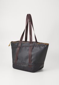Sac fourre-tout en tissu noir avec des bordures festonnées, des accents rouges et des poignées doubles, portant un texte noir ; fermeture éclair avec un cordon doré.
