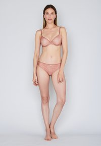 Lacy rose-colored bra with underwire and adjustable straps, paired with matching bikini briefs. Both feature floral patterns and soft textures.
