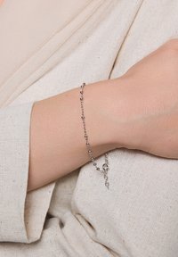 Srebrna bransoletka z okrągłymi koralikami na delikatnym łańcuszku, z zapięciem typu lobster i subtelnymi akcentami łańcuszka.