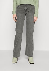 Gray high-waisted jeans with a straight leg fit; features subtle fading and five pockets, paired with light green, glossy heeled ankle boots.