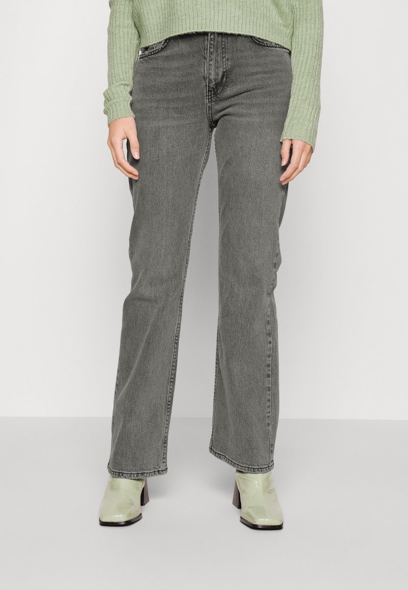 Gray high-waisted jeans with a straight leg fit; features subtle fading and five pockets, paired with light green, glossy heeled ankle boots.