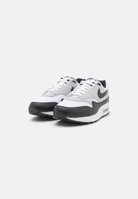 White and grey athletic shoes with black accents, featuring a mesh upper, padded collar, flat laces, and a visible air cushioning unit in the sole.