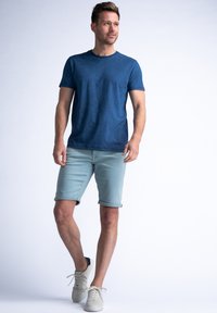 Navyblauw gestructureerd T-shirt gecombineerd met lichtblauwe opgerolde shorts en lichtgekleurde sneakers, met een casual en ademend ontwerp.