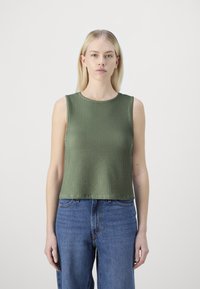 Green ribbed knit sleeveless top with a round neckline, paired with high-waisted blue jeans. Smooth texture, cropped design.
