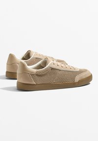 Beige színű sportcipők hálós panelekkel, velúr részletekkel és gumitalppal. Kerek orr és lapos fűzők. Egyszerű dizájn, texturált felületekkel.