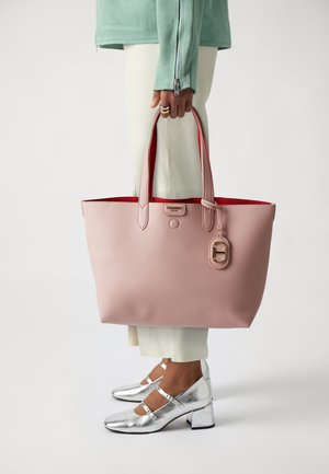 Borsa tote rosa realizzata in materiale testurizzato, con interni rossi, doppi manici e un accento in hardware dorato. Scarpe con tacco quadrato argentato visibili.