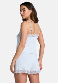 Camiseta de algodón gris con encaje en el borde, combinada con pantalones cortos a juego que presentan detalles de encaje en los dobladillos. Incluye tirantes ajustables.
