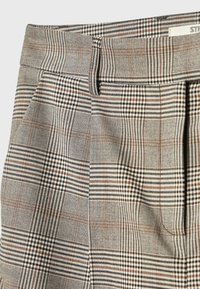 Pantalon taille haute avec motif à carreaux gris, noir et marron, avec passants de ceinture et plis sur le devant.
