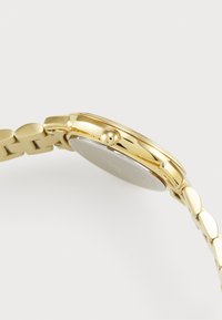 Gold metal wristwatch with a smooth round face, a textured bezel, and a linked band featuring oval-shaped links.