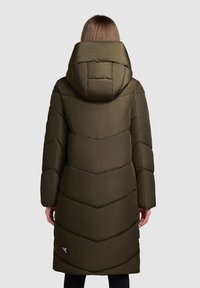 Lange, olijfgroene pufferjas met een capuchon en chevronstiksel. Bevat een gebogen zoom en een klein logo aan de onderkant aan de linkerkant.