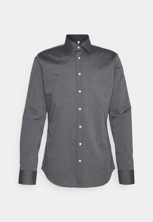 Chemise boutonnée grise foncée avec des manches longues, une texture subtile et un col noir à motif. Dotée de boutons blancs classiques.