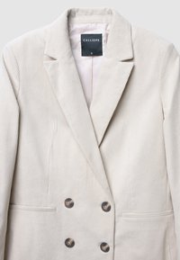 Blazer en velours côtelé beige avec un design croisé, des revers crantés et deux boutons marron, avec une poche unique et une doublure lisse.