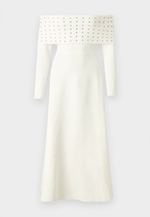 Witte off-the-shoulder jurk met lange mouwen, voorzien van een gestructureerd lijfje versierd met zilveren studs, een uitlopende zoom en gegolfde randen.