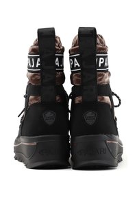 Bottines noires et brunes avec une tige brillante, des languettes de traction, une semelle texturée et des sangles avec logo. Inclut des éléments en métal distinctifs et des détails de logo.